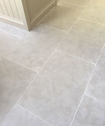 a white toilet sitting in a bathroom next to a sink and counter top on a tiled floor