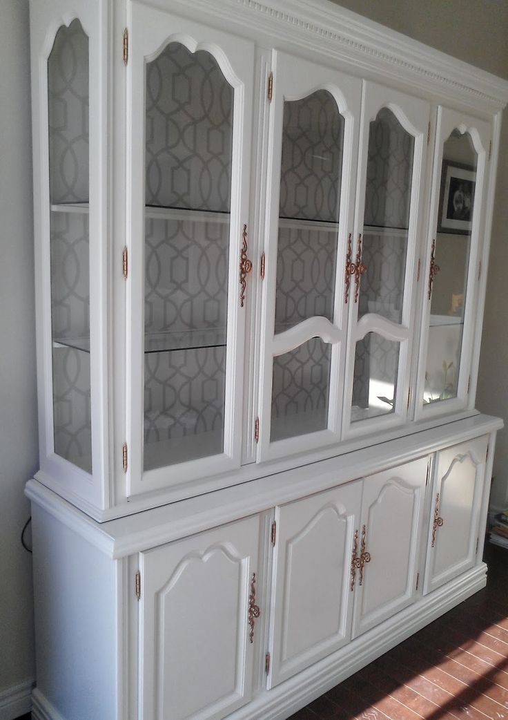 a large white china cabinet with glass doors