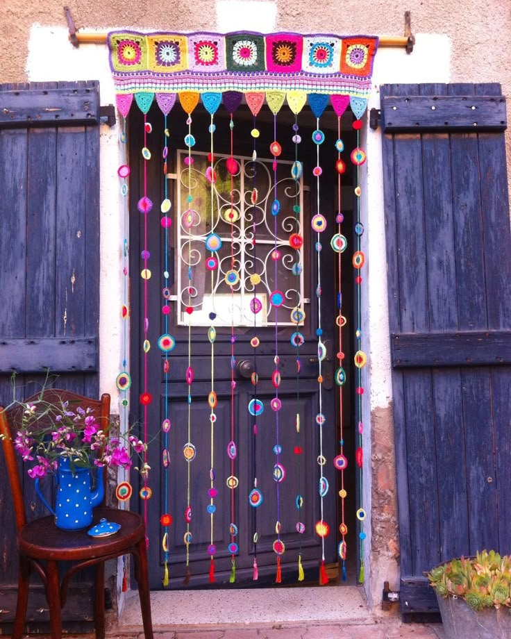 a wooden chair sitting in front of a door decorated with colorful beads and decorations on it