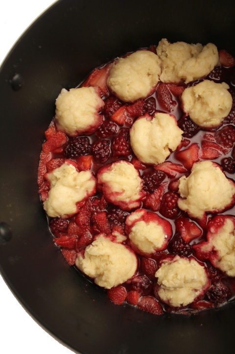 the food is being cooked in the pan with strawberries and ice cream on top