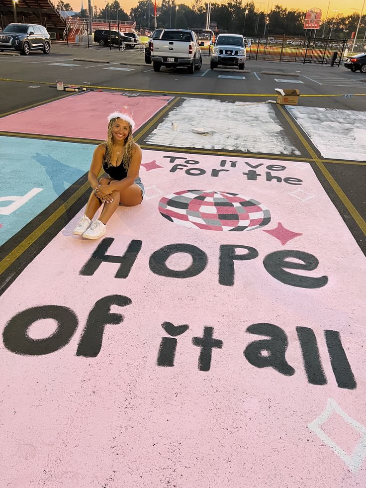 a woman sitting on the ground in front of a sign that says hope of it all