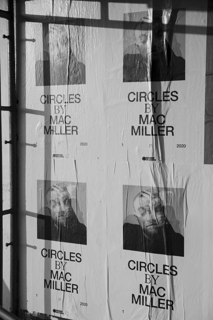 posters on the side of a building in black and white, with shadows coming from them