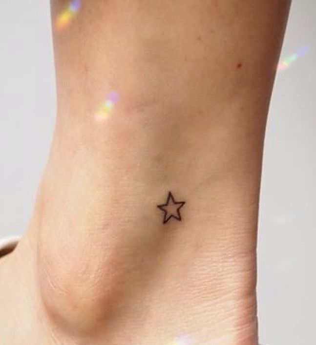 a small star tattoo on the side of a woman's ankle is shown in black ink