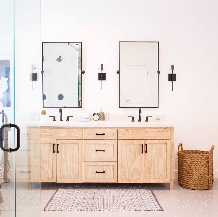 a bathroom with two sinks and mirrors on the wall next to a rug in front of it