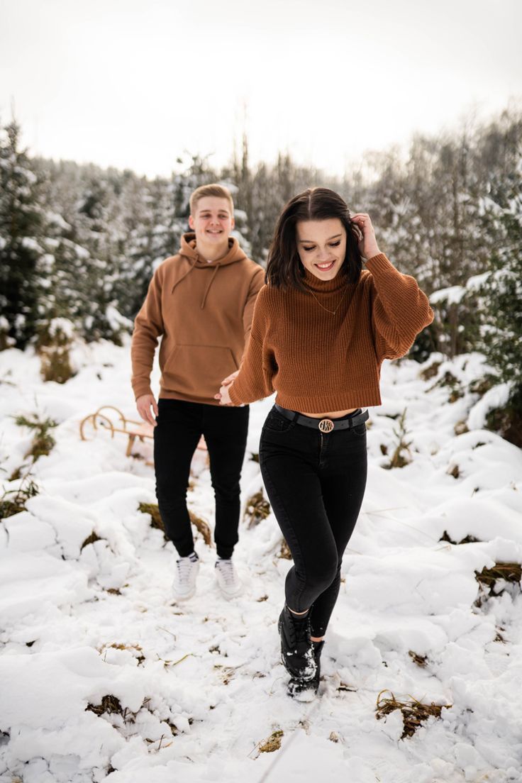 a man and woman walking through the snow