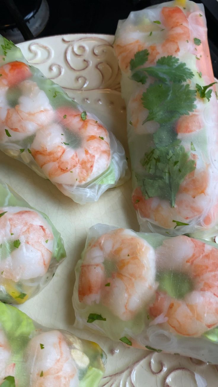 several shrimp rolls on a plate with cilantro and parsley