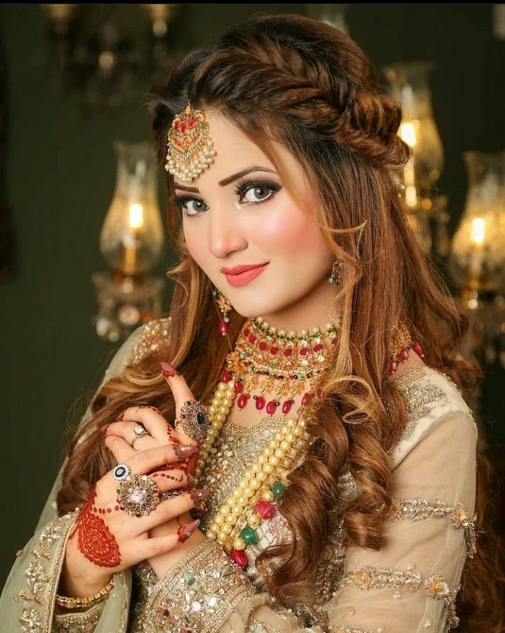 a woman with long hair and jewelry on her head, posing for a photo in front of a chandelier