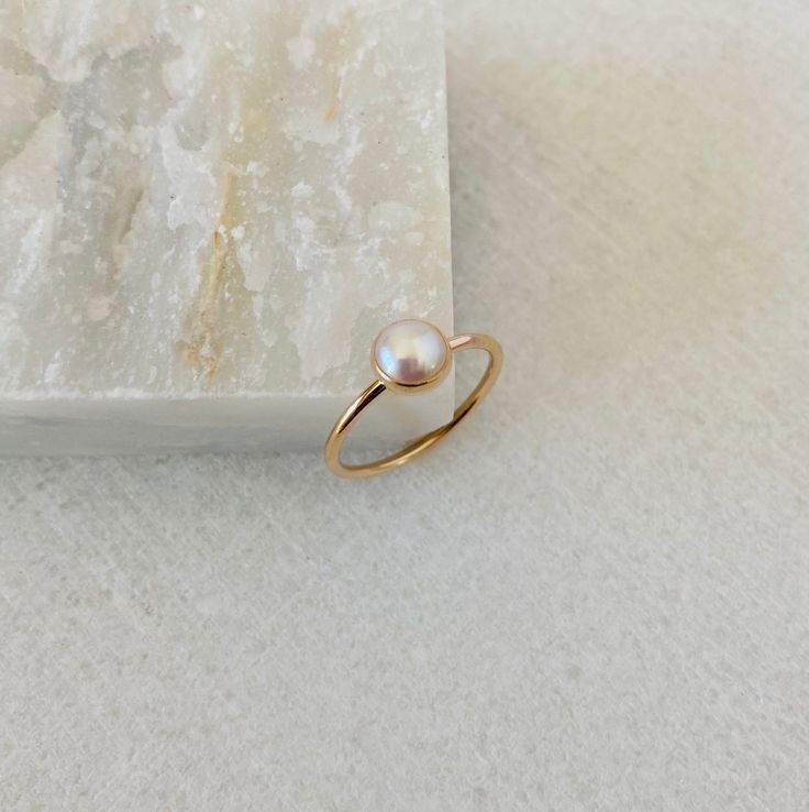 This dainty pearl ring will be handmade to order in your size.  Created with a natural 6mm white freshwater pearl, it will make a beautiful birthday gift for a July born person.  Please select the material and band width at the checkout. *Listing is for a pearl ring only. *Every pearl is unique but will closely match the featured one.  Model wears ring size 5, 1.3mm band 14k Yellow Gold Rings With Pearl Charm, Minimalist Pearl Drop Ring For Gift, Yellow Gold Pearl Birthstone Ring For Promise, Delicate Round Band Pearl Promise Ring, Minimalist Pearl Ring With Birthstone, Minimalist Pearl Drop Rings As Gift, Yellow Gold Pearl Promise Ring With Birthstone, Dainty Pearl Birthstone Ring For Anniversary, Dainty Pearl Promise Ring With Birthstone