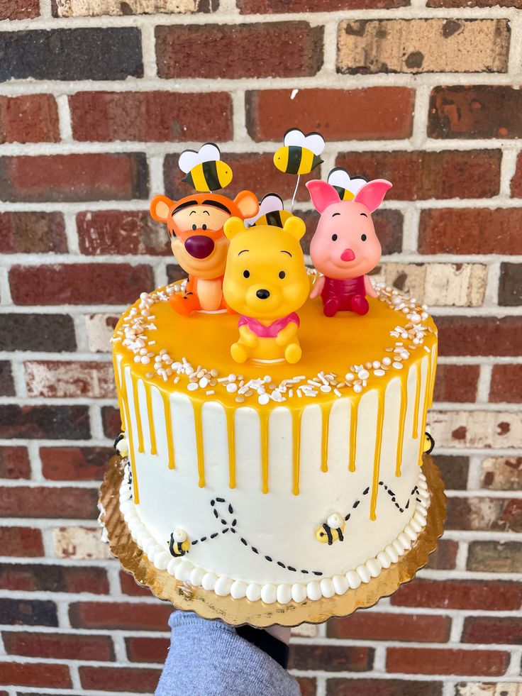 a winnie the pooh cake is decorated with fondant and honey drips on top