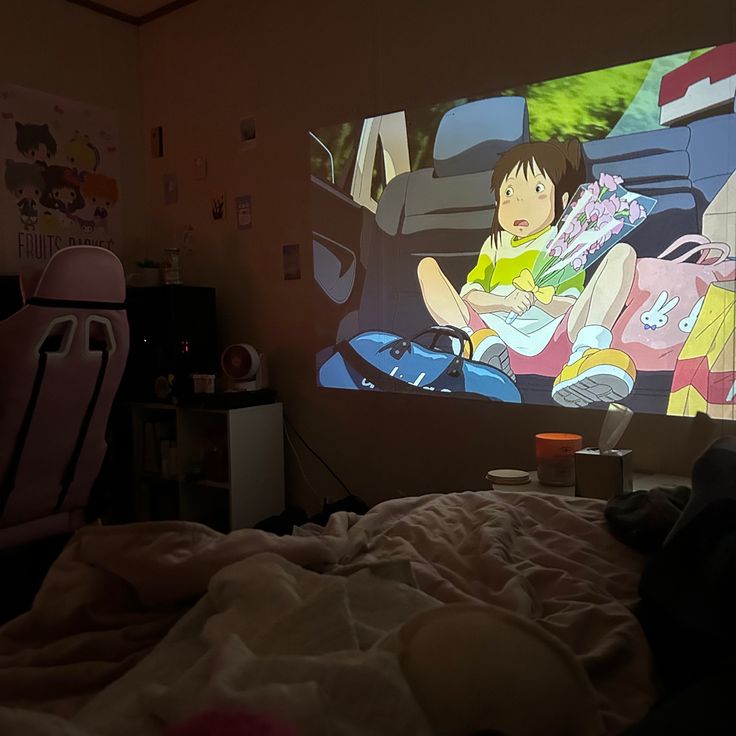 a child is sitting on a bed in front of a large television screen with an anime scene