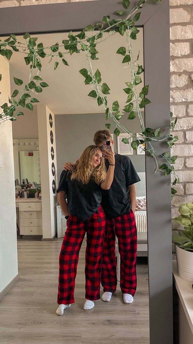 two people standing in front of a mirror with their arms around each other and one person taking a selfie