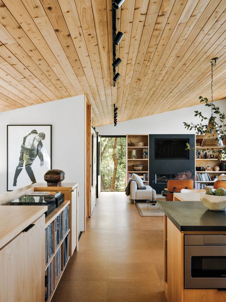 an open kitchen and living room area with wood ceilinging, white walls and cabinets