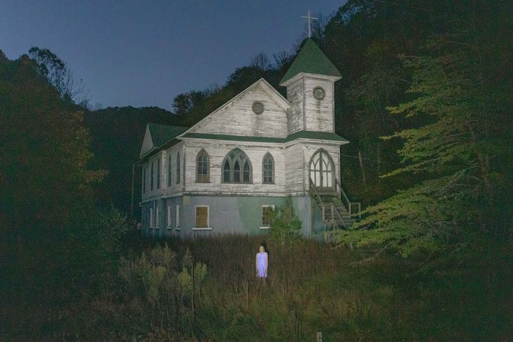 a person standing in front of a church at night with the moon shining on them