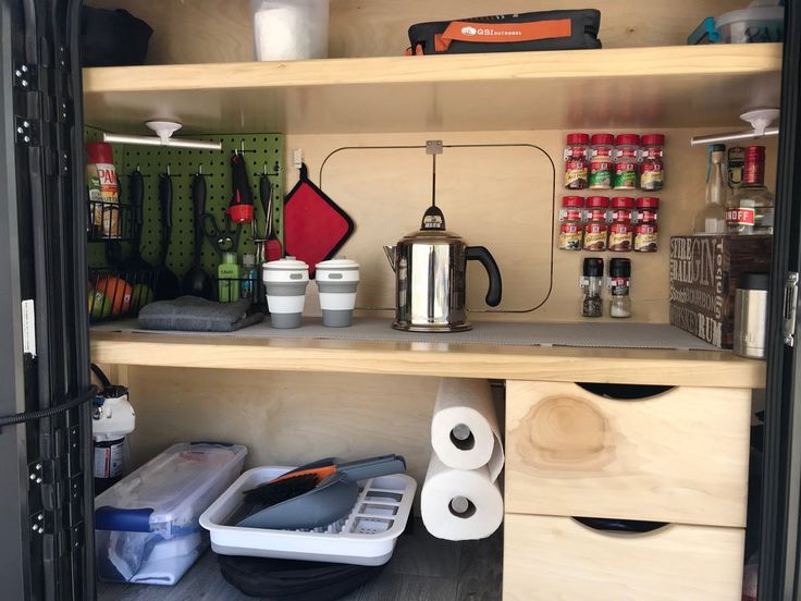 the inside of a kitchen cupboard with various items on shelves and other things in bins