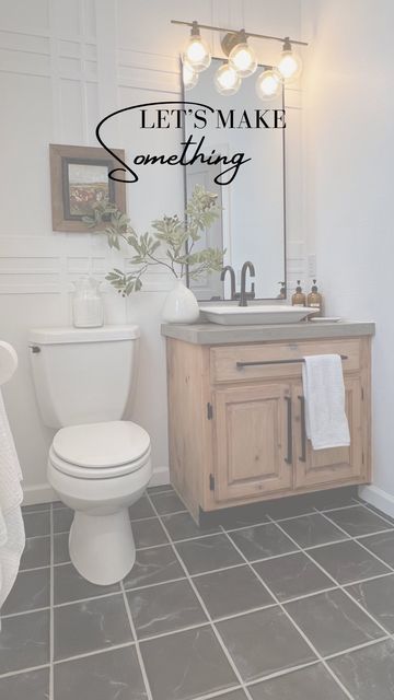 a bathroom with a toilet, sink and mirror that says let's make something