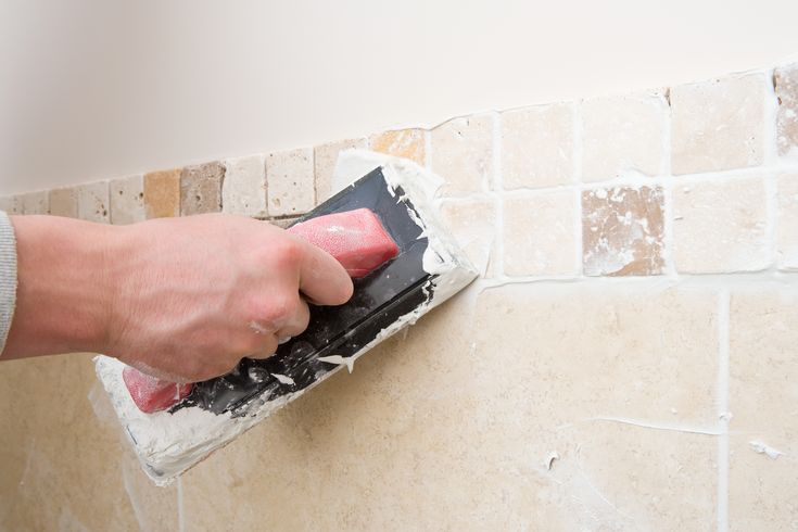 a person using a sponge to clean a tile wall