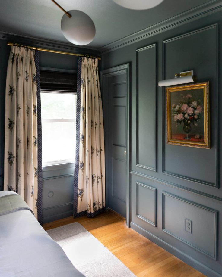 an empty bedroom with blue walls and wood flooring is pictured in this image, there are curtains on either side of the bed