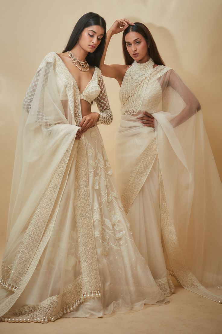 White saree with thread and pearls hand embroidered borders. Comes with a blouse and an underskirt.
Components: 3
Pattern: Hand embroidered
Type Of Work: Thread, Pearls
Neckline: Halter
Sleeve Type: Sleeveless
Fabric: Tulle, Viscose georgette
Color: White
Other Details: 
Heavily embroidered blouse
Closure : Blouse - Back hooks
Note : Lehenga set worn by the other model is not for sale.
Occasion: Wedding - Aza Fashions Traditional Georgette Pre-draped Saree With Pearl Embroidery, Traditional Tissue Silk Lehenga With Pearl Embroidery, Pearl Embroidered Chanderi Sets For Reception, Chanderi Sets With Pearl Embroidery For Reception, Reception Sets With Pearl Embroidery In Saree Shape, Wedding Saree With Pearl Embroidery For Festivals, Traditional Semi-stitched Pre-draped Saree With Pearl Embroidery, Bollywood Pearl Embroidered Dupatta For Reception, Traditional Pearl Embroidered Pre-draped Saree For Festive Occasions