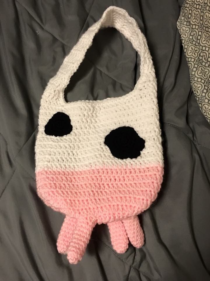 a crocheted pink and white purse with black eyes