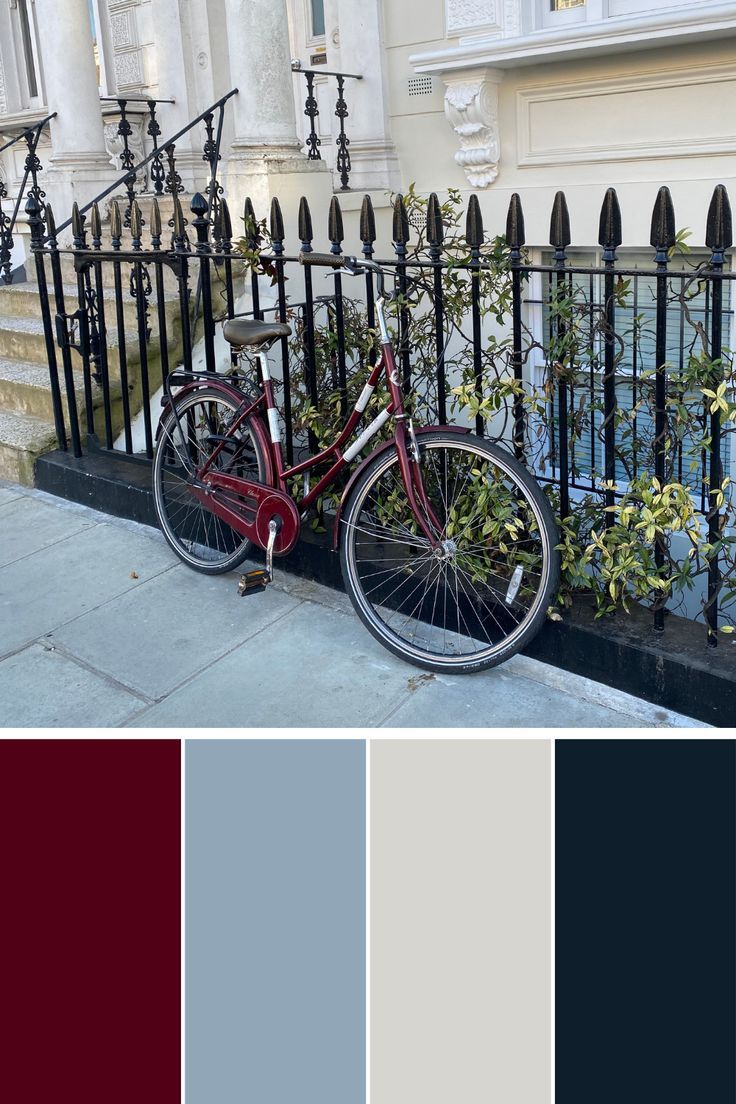 a red bike parked next to a black iron fence with flowers growing out of it