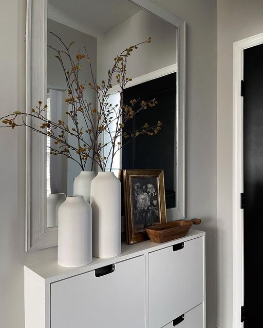 a white dresser with two vases and a framed photograph on it's side