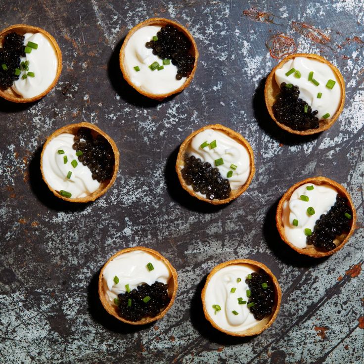 small desserts with cream and black cauliflower are arranged on a metal surface