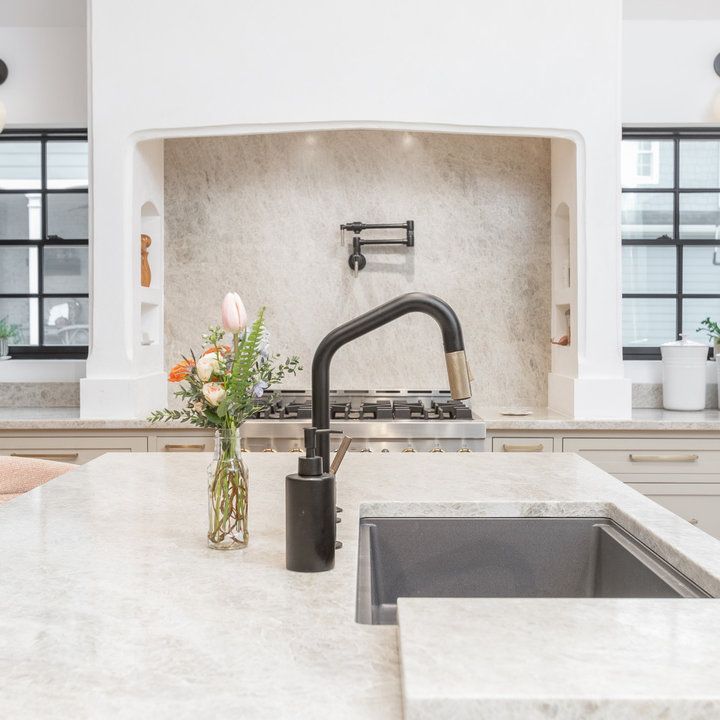 a vase with flowers sitting on top of a kitchen counter next to a sink and stove