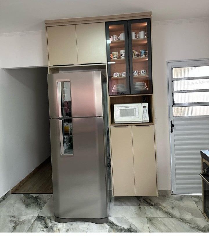 a refrigerator freezer sitting inside of a kitchen next to a microwave oven and cabinets