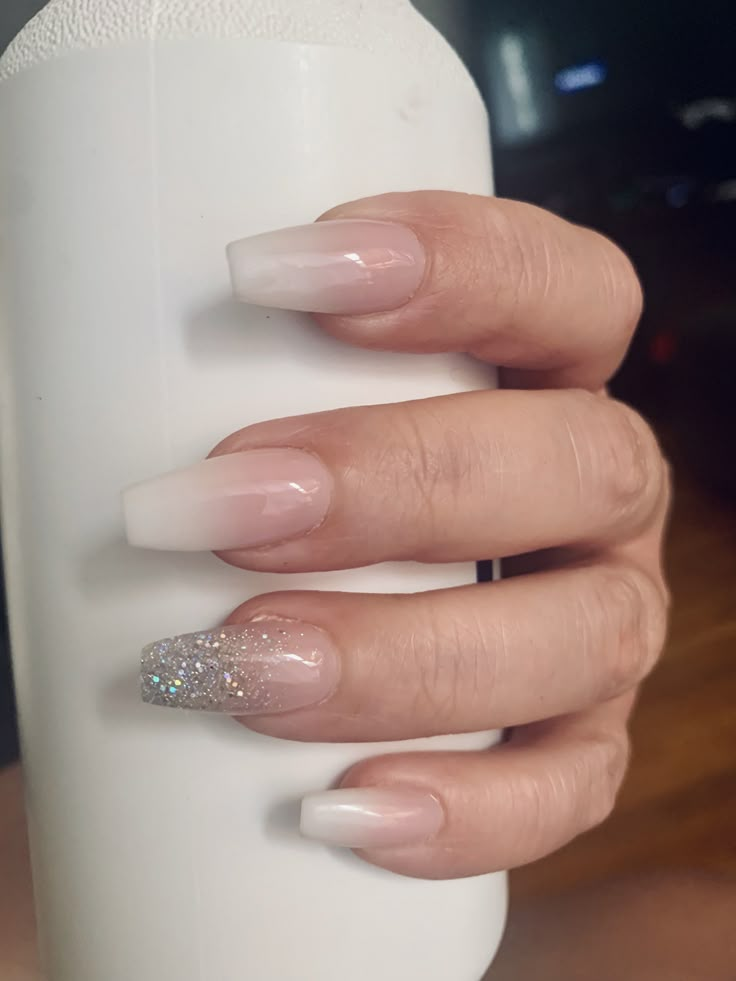 a woman's hand holding a white bottle with some glitter on the tip of it