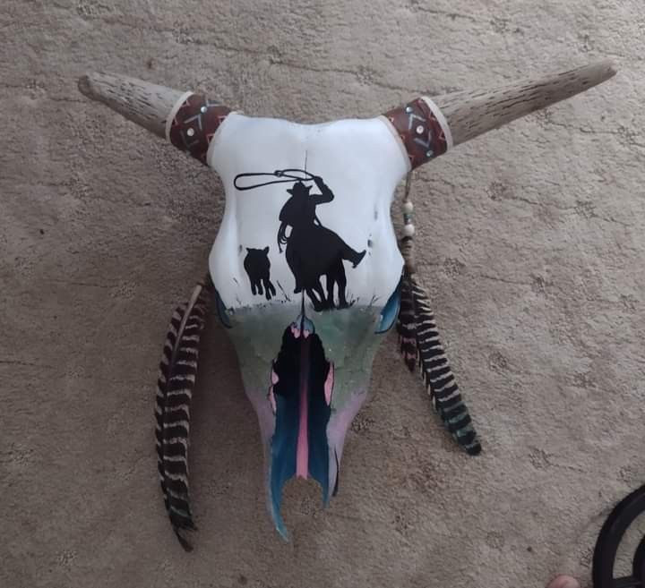 a cow skull with long horns and an animal's head painted on the side