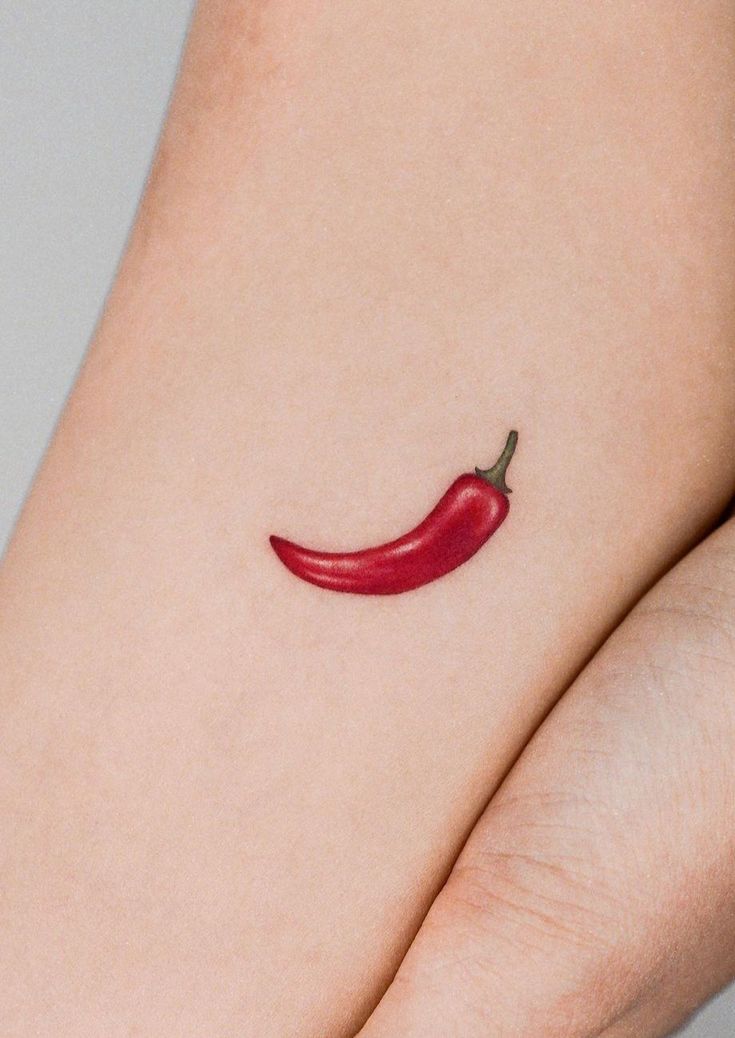 a red chili pepper tattoo on the arm