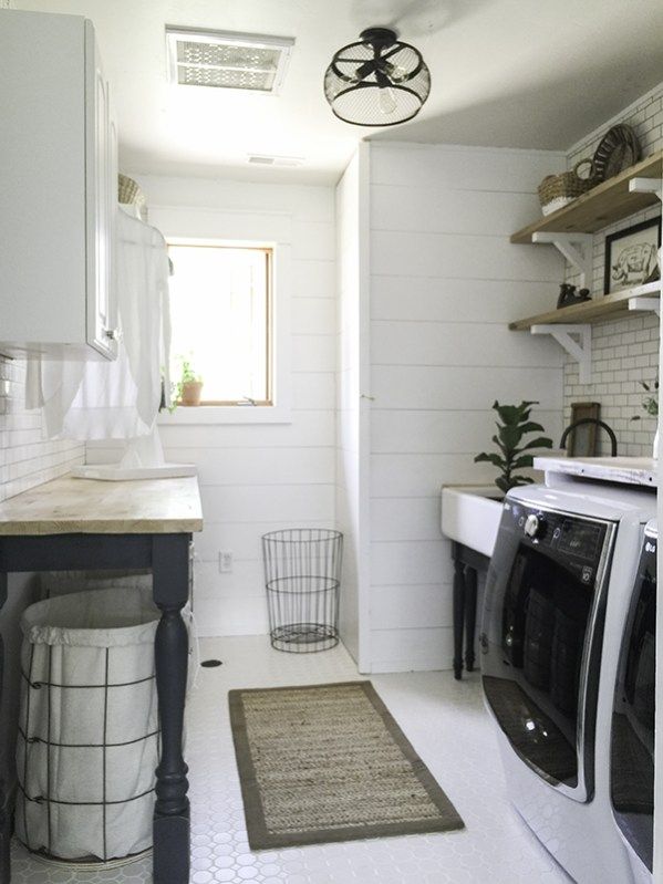 a washer and dryer in a small white laundry room with open shelving