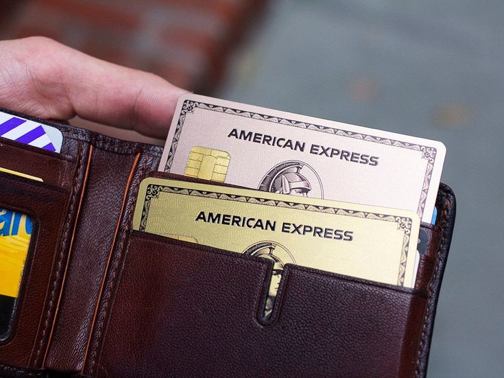 a person holding an american express credit card in their wallet