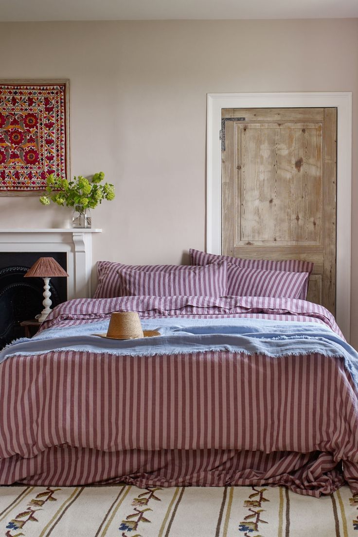 a bed sitting in a bedroom next to a fire place under a painting on the wall