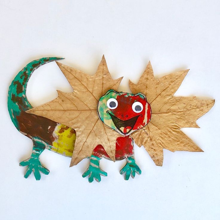 a paper plate with a lizard on it and leaves attached to the back of it