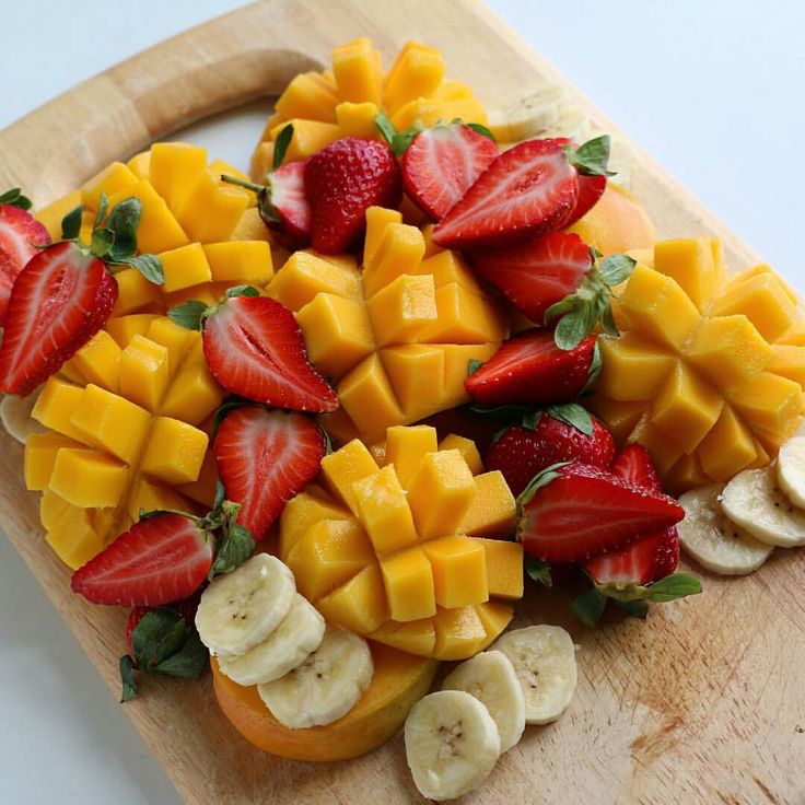 sliced fruit arranged on a cutting board with bananas and strawberries