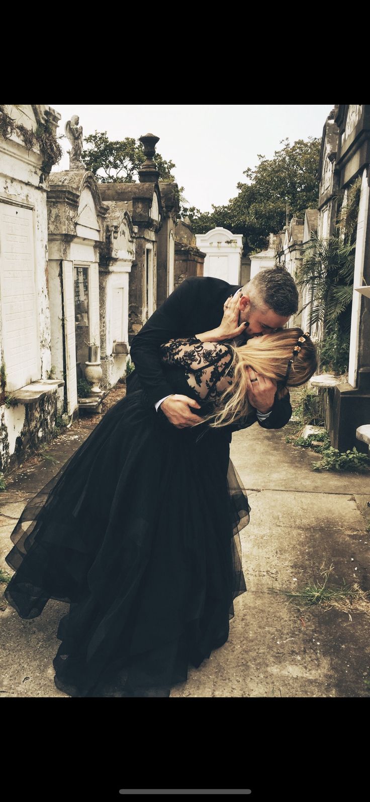 a man and woman are kissing in front of an old cemetery with headscarves wrapped around their necks