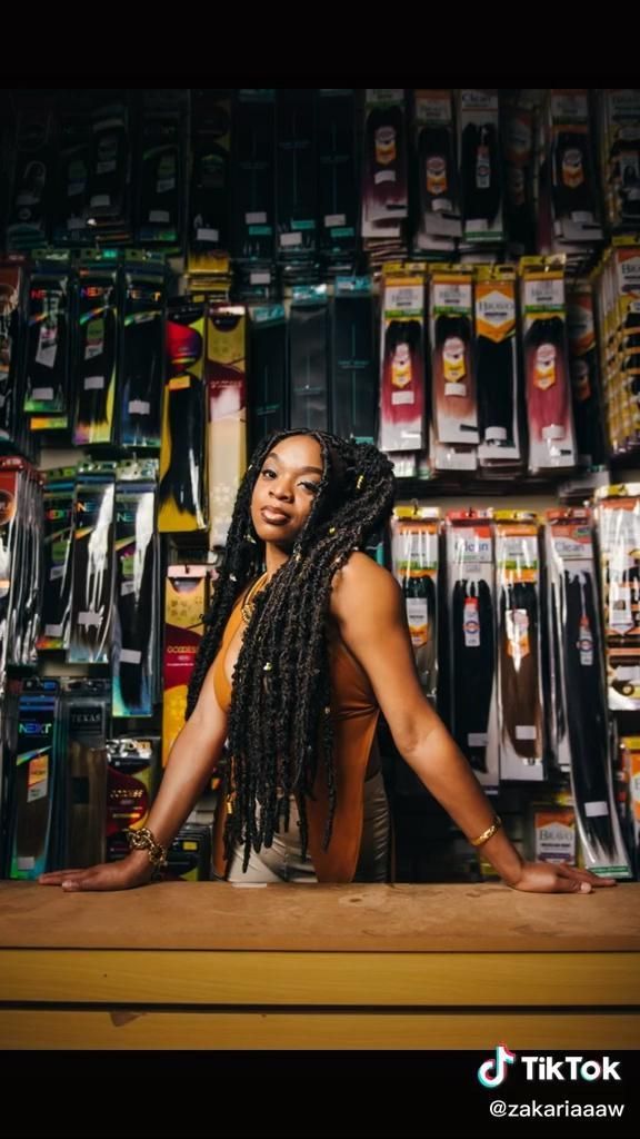 a woman with dreadlocks standing in front of a store display filled with bottles