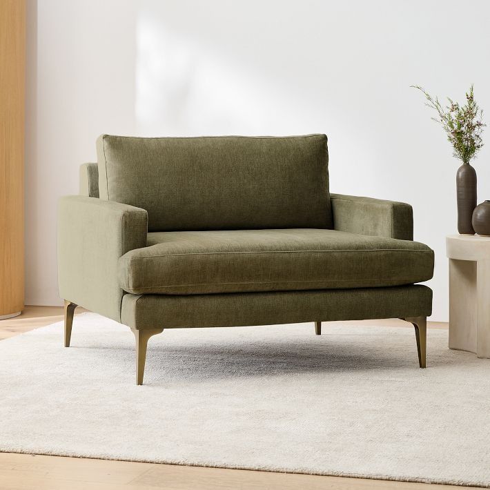 a green chair sitting on top of a white rug next to a vase and table