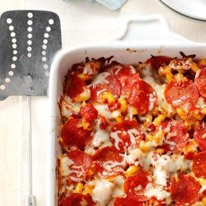 a casserole dish with tomatoes and cheese in it next to utensils