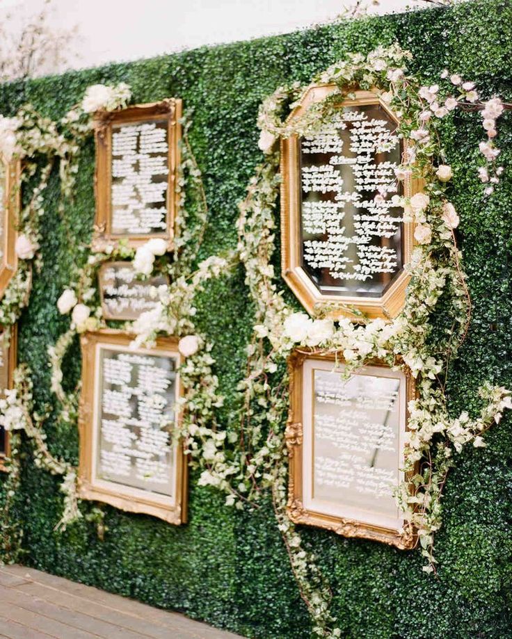 a wall covered in greenery with pictures and seating signs on it's sides