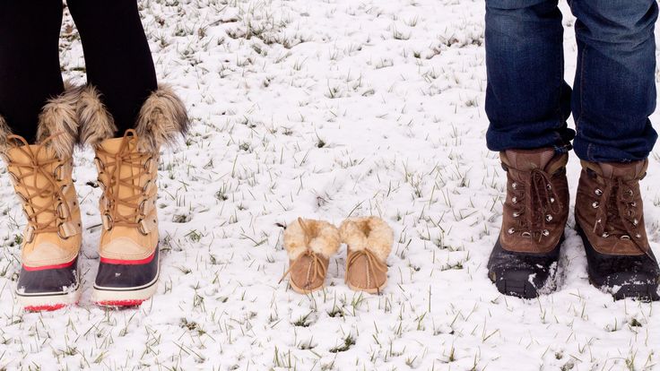 two people standing next to each other in the snow wearing winter boots and holding hands