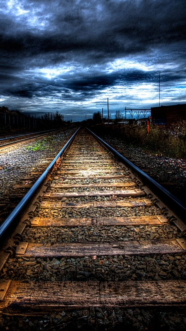 an empty train track with dark clouds in the background