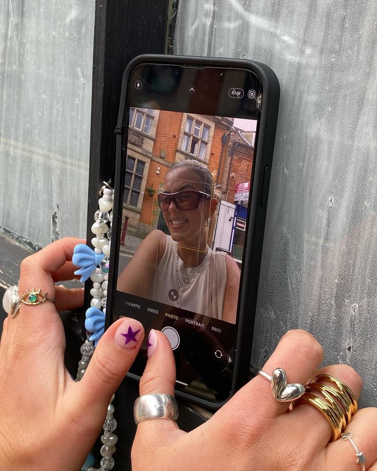 two hands are holding an iphone with a woman's face on the phone screen