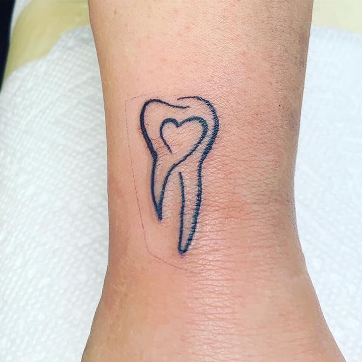 a small tattoo on the ankle of a person with a tooth shaped like a heart