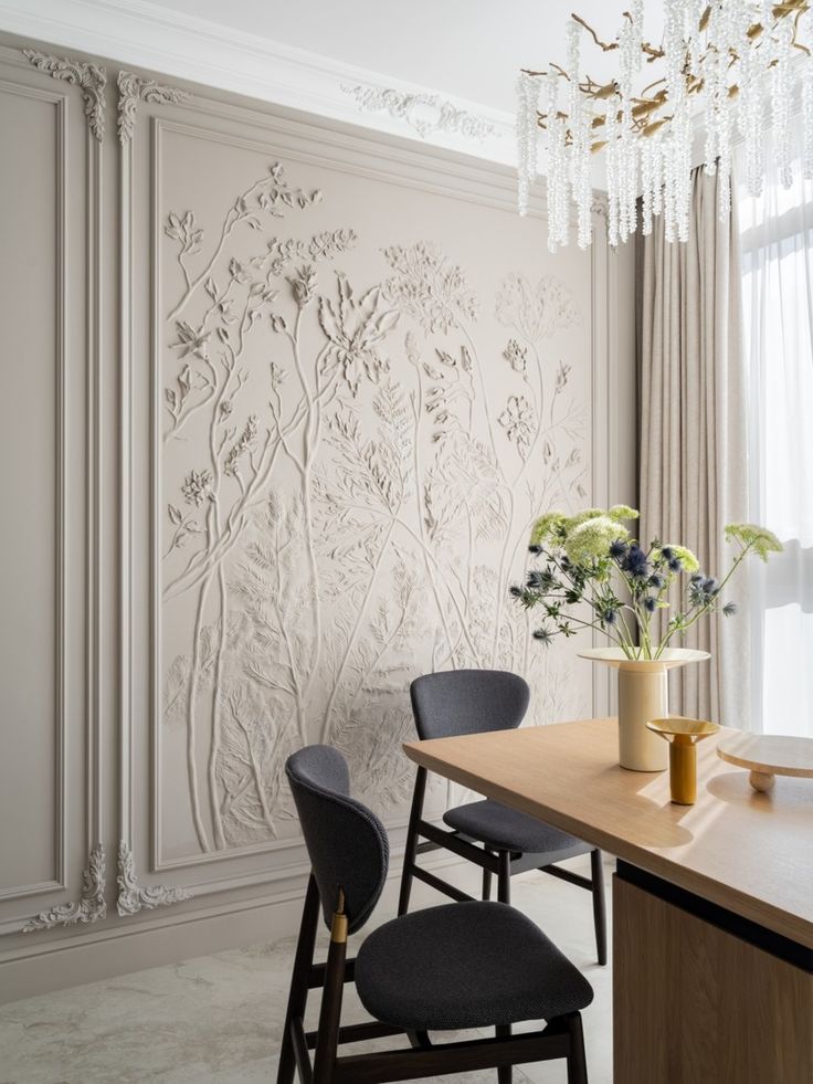 a dining room table with two chairs and a vase filled with flowers