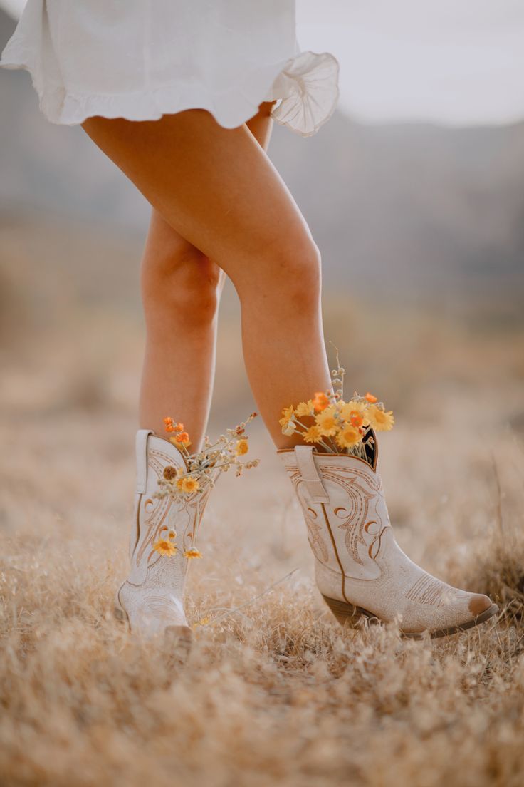 a woman's legs wearing cowboy boots with flowers in them