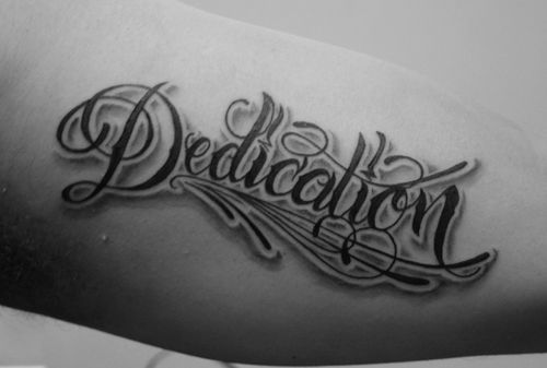 a black and white photo of a tattoo with the word dedication in cursive writing