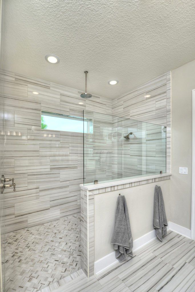 a bathroom with a walk in shower next to a bathtub and two towels hanging on the wall