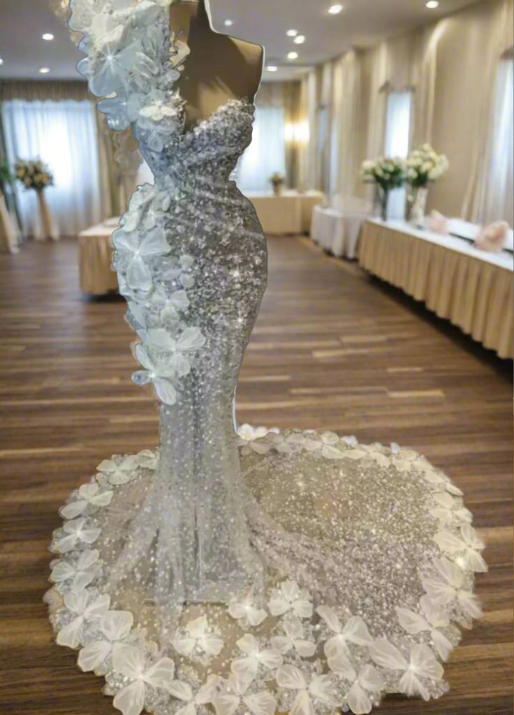 a wedding dress on display in a room with tables and white tablecloths behind it